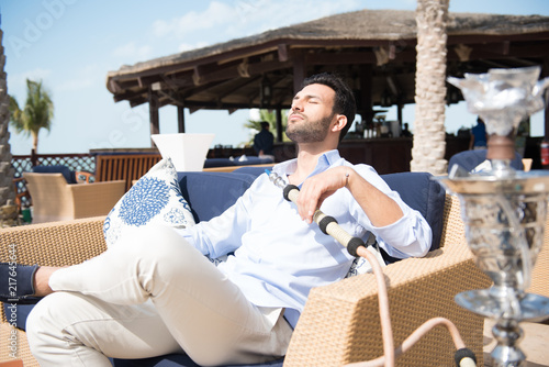 Expat man smoking sheesha at restaurant.