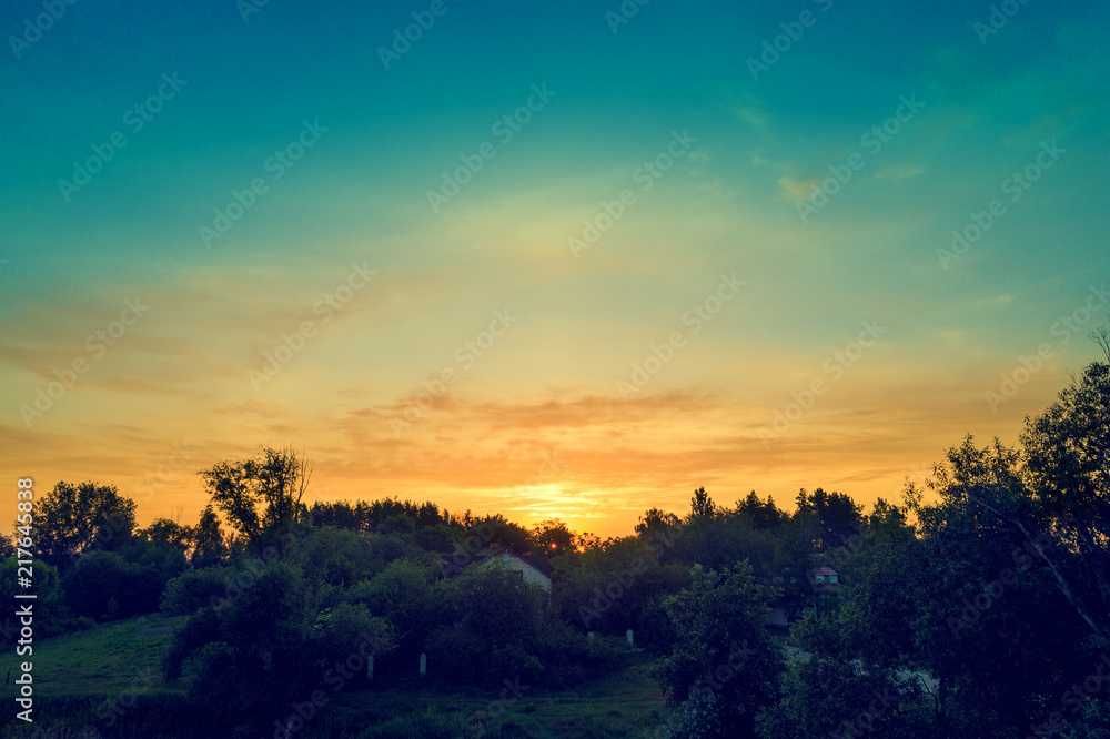 Rural landscape in evening at sunset. Silhouette of village against beautiful gradient evening sky