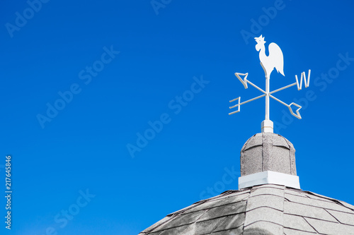 White rooster weather vane on blue sky