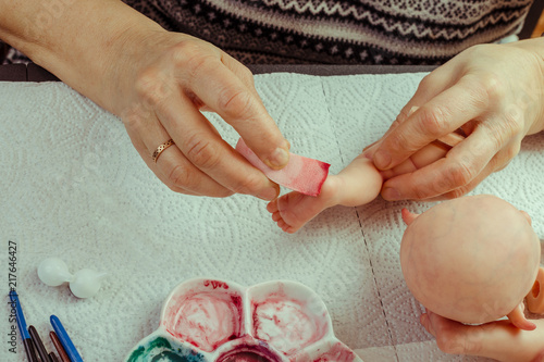 фотографія Female hands make dolls of BJD or reborn in the workplace