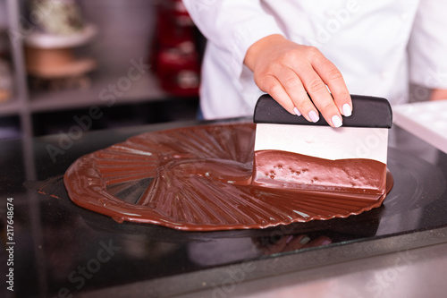 Chocolate confectionary. Skillful experienced chocolatier making white jacket cooking chocolate confectionary photo