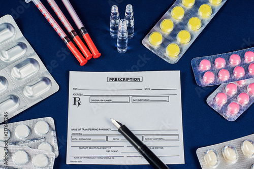 prescription, pen, tablets, syringes and three ampoules on a blue velvet background