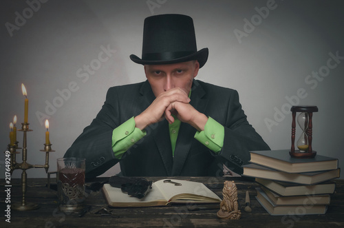 Severe detective agent man in a bowler hat is sitting by the table. Detective or spy agent or police inspector or mafia boss concept. photo