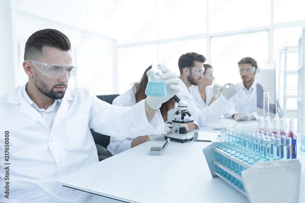 biochemist with flask Petri sitting at a Desk StockFoto Adobe Stock