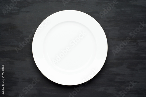 Empty plate on dark black wooden background. Top view with copy space