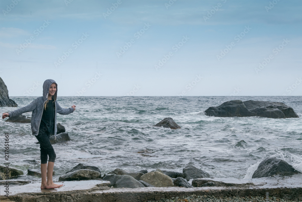 A teenage girl in a sweater on a raging cold sea. Rest on the sea, the ocean in bad weather. A teenage girl in a sweater on a raging cold sea. Rest on the sea, the ocean in bad weather.