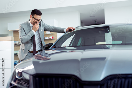 Happy businessman posing near his new automobile at the dealership showroom © zorandim75