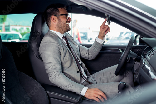 Handsome businessman is sitting in a new car in car dealership