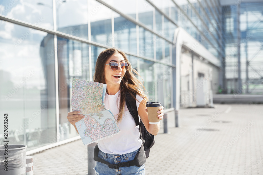 Happy young tourist at airport at window with a map and coffee hurrying to catch a plane.  traveling along Europe, freedom and active lifestyle concept

