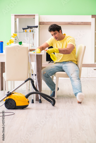 Injured man on crutches cleaning house