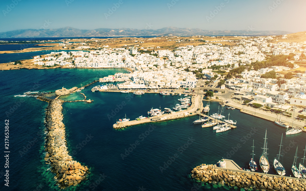 Aerial drone bird's eye view shot of scenic small town of Naoussa with small traditional Greek style white houses and the seaport