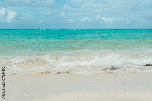 Small waves from a storm in the Indian ocean. Clean water runs on the light sand of the beach