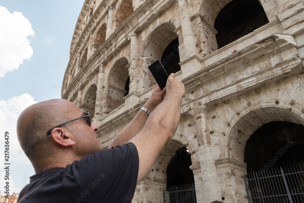 Male tourist taking a photo of the famous Roman monument the Colosseum or Flavian Amphitheatre