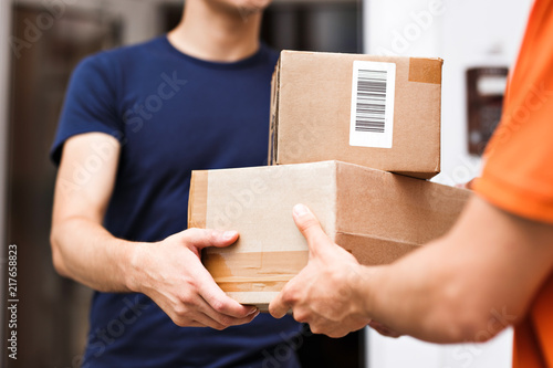 A person wearing an orange T-shirt is delivering parcels to a satisfied client. Friendly worker, high quality delivery service.