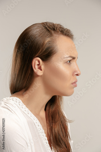 Angry woman looking at camera. Aggressive business woman standing isolated on gray studio background. Female profile portrait. Human emotions, facial expression concept.