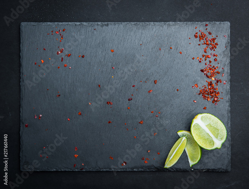 Gray textured board with laim and pepper on the dark background photo