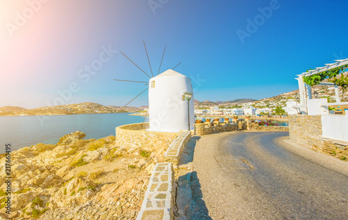 Old white windmill on the cliff in front of water and beautiful blue sky at sunny day  Paros  Greece