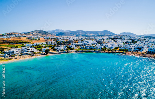 Aerial bird's eye view of a Greek turquoise bay and the whitewashed traditional houses on the coastline and mountains on the background