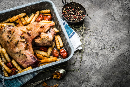 Homemade turkey wing with french fries and spices in baking tray on gray table