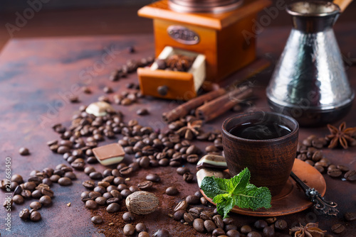 a cup of coffee, coffee beans and fresh mint leaves on a brown background. Copy space for you text