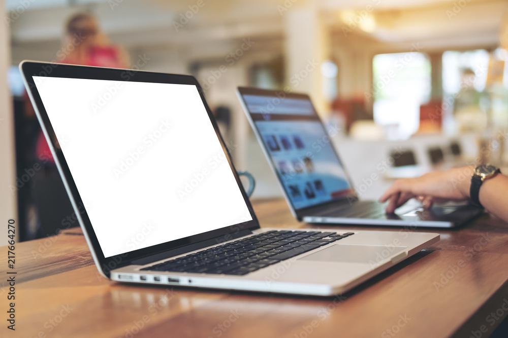 Mockup image of woman's hands using and typing on laptop with blank white desktop screen on wooden table in office Mockup image of woman's hands using and typing on laptop with blank white desktop screen on wooden table in office