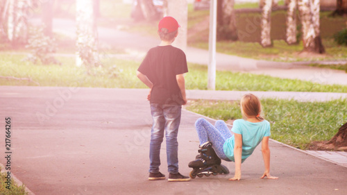 Boy teaches girl to roller skate at sunset
