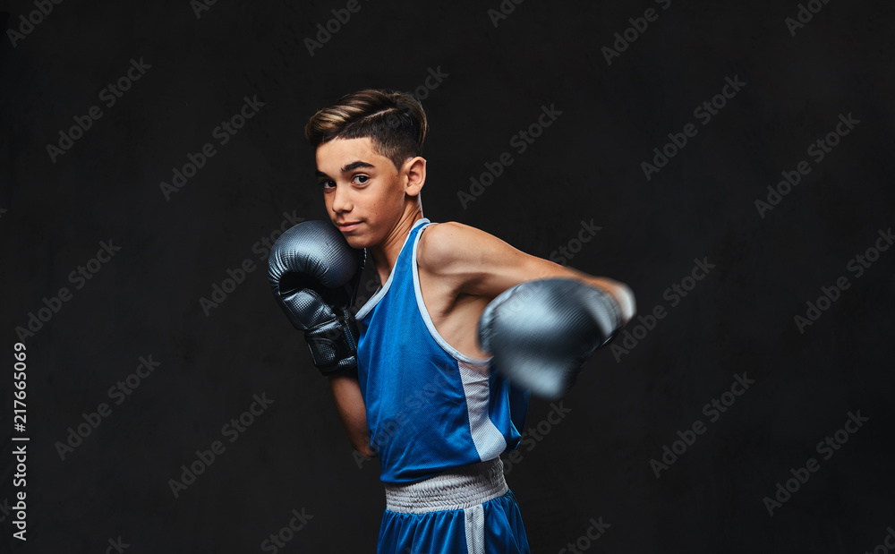 Handsome young boxer during boxing exercises, focused on process. Isolated on the dark background.