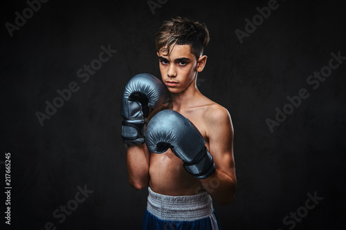 Portrait of a handsome shirtless young boxer wearing gloves. Isolated on a dark background. © Fxquadro