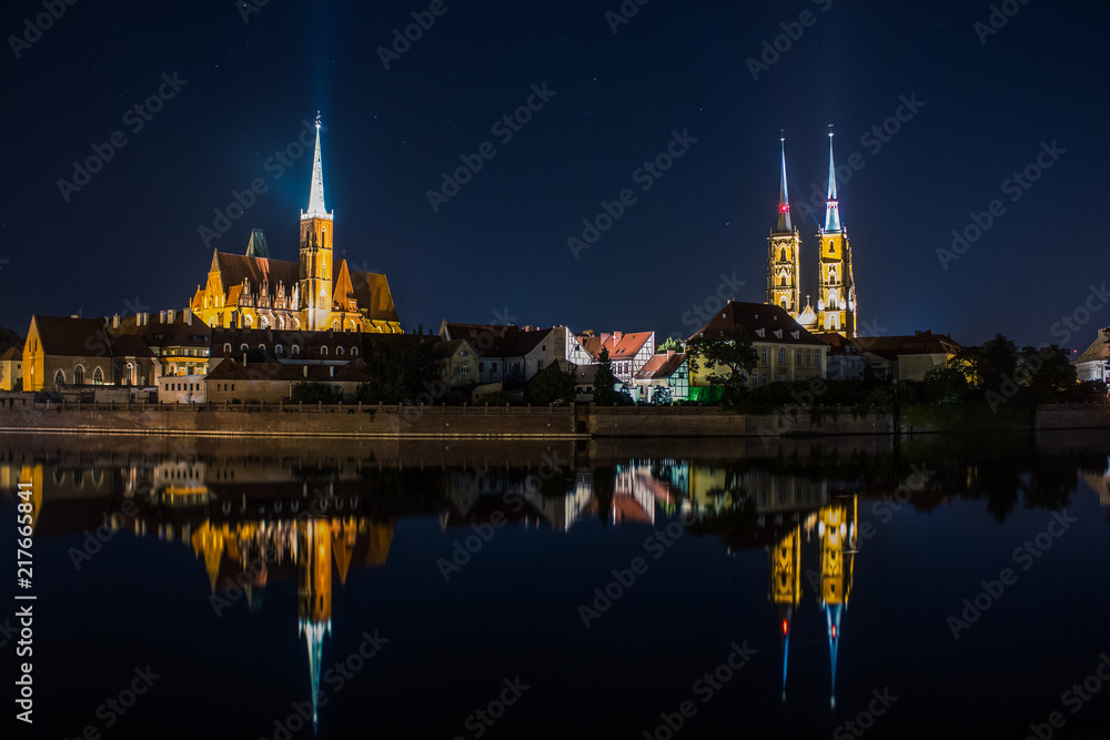 beautiful long exposure night photography colorful concept of old medieval city waterfront district with two cathedral church small houses lanterns illumination and reflection on water  