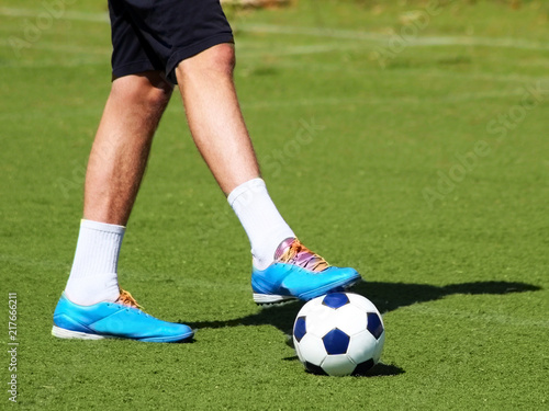 Men s feet and soccer ball on green field
