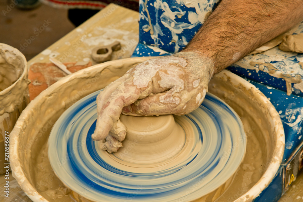 The potter's hands make a ceramic vase on a potter's wheel