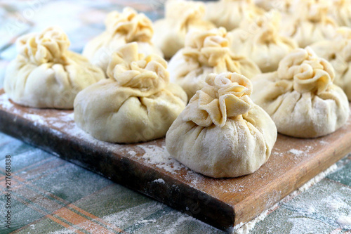 Homemade delicious raw manti (turkish ravioli) on a board sprinkled with flour. Preparation of Manti. Manti, Mantu or Manty Momos, Jiaozi, Dyushbara, Sikkim, Darjeeling