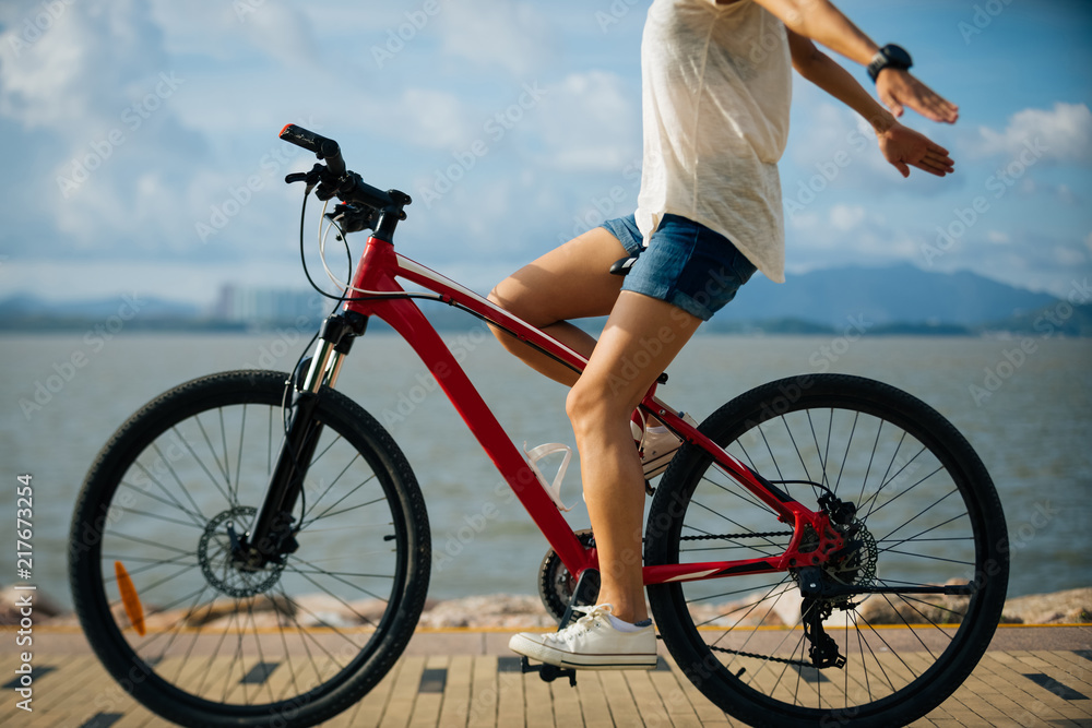 Free woman riding a bike on sunny seaside with arms outstretched Free woman riding a bike on sunny seaside with arms outstretched