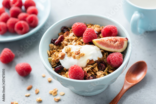 Granola bowl with yogurt, figs and raspberries. Healthy breakfast, healthy snack, concept of healthy lifestyle and eating. Closeup view, selective focus. Blue crockery