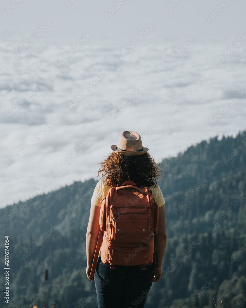 Woman traveler hipster with backpack looking forward at amazing mountains and valley view.
