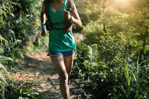 Fit woman trail runner running in morning forest