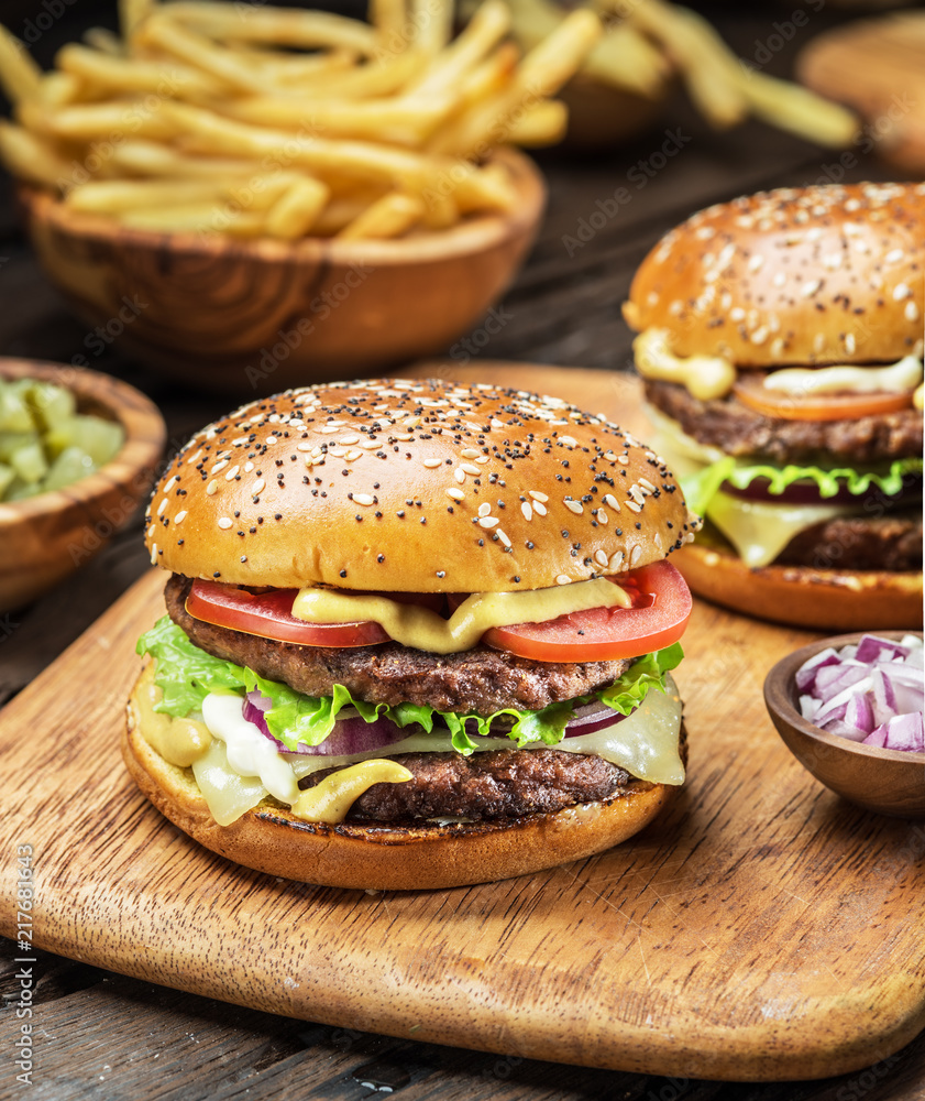 Hamburgers and French fries on the wooden tray. Hamburgers and French fries on the wooden tray.