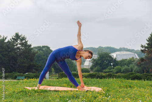 Breathing and yoga. Appealing woman wearing blue leggings and sport shirt breathing slowly while doing yoga