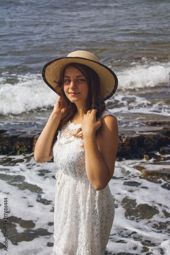 Beautiful girl in white dress and hat by the sea