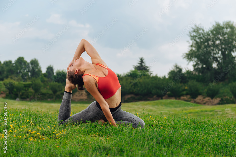 Top and leggings. Dark-haired woman wearing red top and grey leggings stretching during her morning gymnastics Top and leggings. Dark-haired woman wearing red top and grey leggings stretching during her morning gymnastics