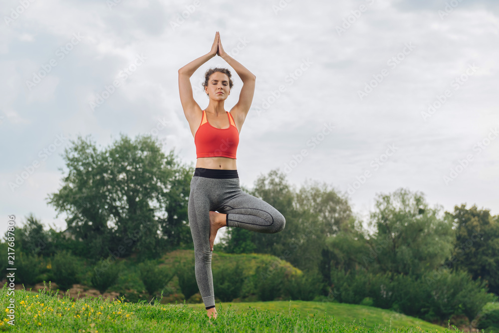 Red sport top. Athletic woman wearing bright red sport top doing yoga being fond of gymnastics and sport Red sport top. Athletic woman wearing bright red sport top doing yoga being fond of gymnastics and sport