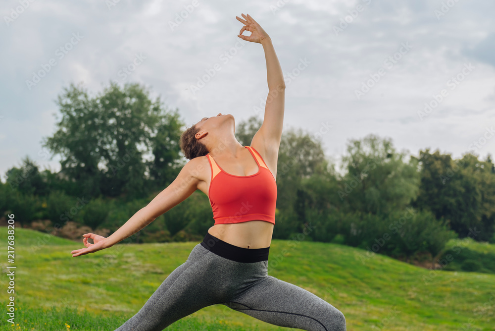 Fototapeta premium Graceful woman. Slim graceful woman feeling simply amazing and relaxed while doing yoga poses outdoors