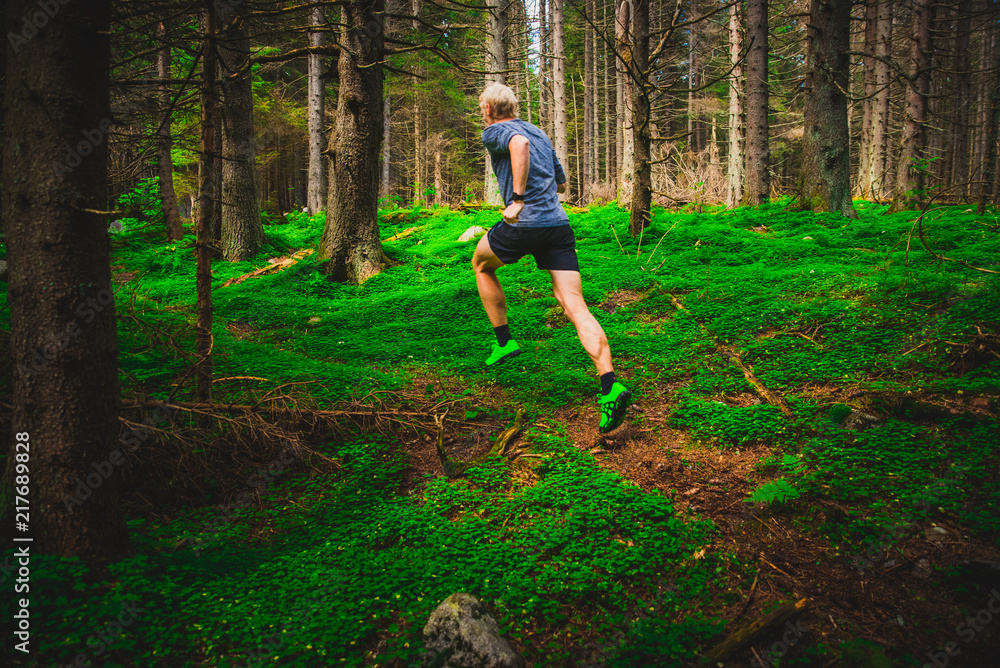 Athletic man running on trail through green forest. Sport photo, trail Athletic man running on trail through green forest. Sport photo, trail