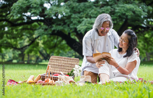 happy senior couple reading books, after retirement in the park,spending time and relaxing time concept..
