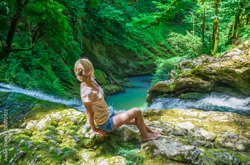 beautiful girl sits on top of a waterfall and admires a beautiful view, Georgia