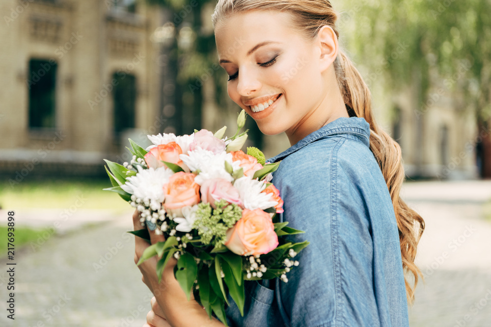 smiling young woman looking at flower bouquet smiling young woman looking at flower bouquet