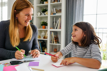 Proud mother teaching child at home how to write. Early education