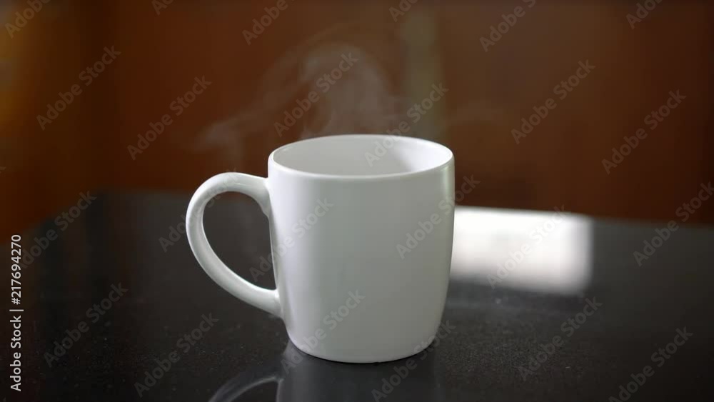 Hot coffee with smoke in white cup on black marble table Hot coffee with smoke in white cup on black marble table