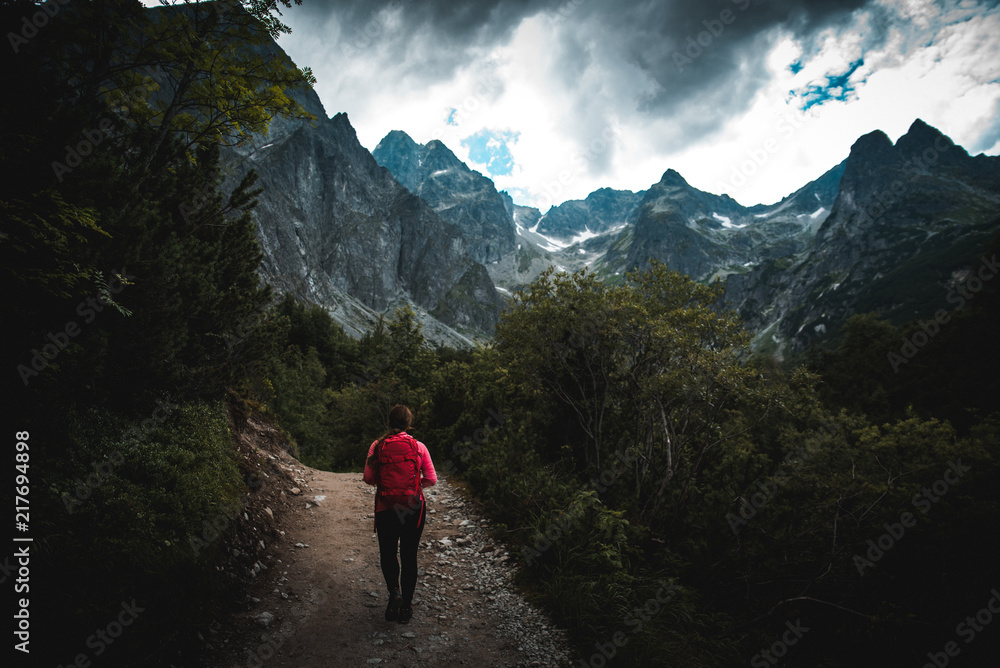 Female with red backpack in dark mountains