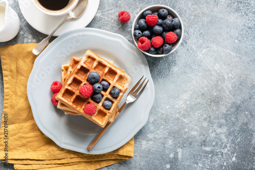 Belgian waffles, coffee and berries on concrete background. Top view, copy space for text